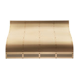 elegant curved silhouette brushed brass custom range hood with vertical rivet straps and bottom framed mesh grille for farmhouse luxury kitchen front view