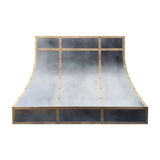 curved antique zinc custom range hood with antique brass grid trim and decorative rivets front view